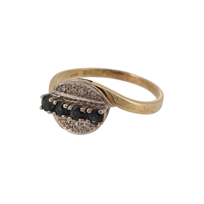 Add classic gemstone colour to your jewellery collection with this pre-owned 14ct yellow gold diamond and sapphire twist-style ring, featuring round sapphires and diamond detailing in a flowing design.

Design: The ring features a distinctive twist-style design, with the setting flowing across the front of the band to create an elegant and eye-catching appearance.
Material: Made from 14-carat yellow gold, the warm gold tone complements the rich blue colour of the sapphires and the diamond detailing.