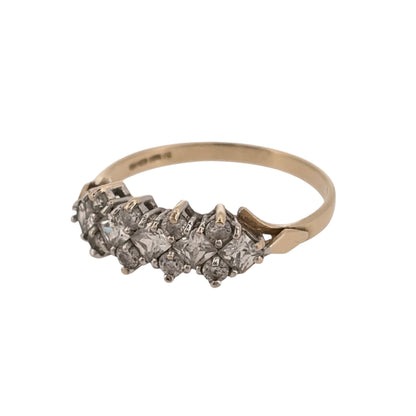 Add classic stone-set detail to your jewellery collection with this pre-owned 9ct yellow gold cubic zirconia cluster band ring, featuring a combination of round and square-cut stones.

Design: The ring features a cluster-style band design, combining round and square-cut cubic zirconia stones across the front for a detailed and distinctive appearance.
Material: Made from 9-carat yellow gold, the warm gold tone provides a classic setting for the cubic zirconia stones.