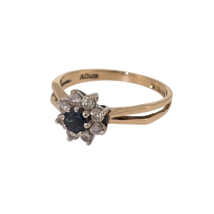 Add a classic piece to your jewellery collection with this pre-owned 18ct yellow gold diamond and sapphire cluster ring, featuring a beautiful round sapphire surrounded by diamonds.

Design: The ring features a traditional cluster design, with a central blue sapphire surrounded by diamonds, creating an elegant and timeless appearance.
Material: Made from 18ct yellow gold, offering a warm gold finish that complements the sapphire and diamonds.