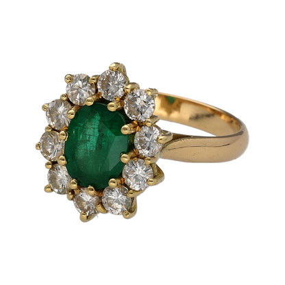 Make a truly luxurious statement with this pre-owned 18ct yellow gold diamond and emerald cluster ring. Showcasing a magnificent oval emerald surrounded by an impressive halo of brilliant-cut diamonds, this stunning ring combines vibrant colour, exceptional sparkle, and timeless elegance.

Design: The ring is centred by a striking oval emerald measuring approximately 9mm by 7mm.
