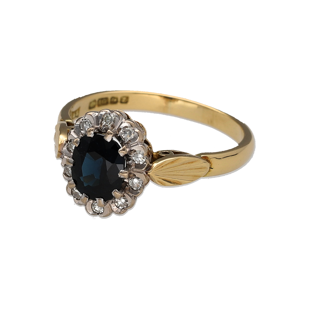 Add classic colour and timeless gemstone styling to your jewellery collection with this pre-owned 18ct yellow gold diamond and sapphire cluster ring, featuring a rich oval sapphire surrounded by diamonds in contrasting white gold settings.

Design: The ring features a classic cluster design with an oval sapphire at the centre, framed by diamonds to create an elegant and eye-catching gemstone arrangement.