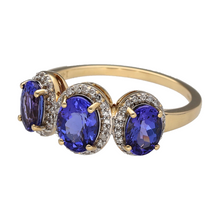 Load image into Gallery viewer, Make a bold and elegant statement with this pre-owned 14ct yellow gold diamond and tanzanite trilogy cluster ring, featuring:

Design: A show-stopping trilogy setting with three vibrant tanzanite stones, accented by sparkling diamonds in a cluster style—symbolising the past, present, and future with rich colour and brilliance.
Material: 14-carat yellow gold, offering a warm, polished finish that complements the vivid violet-blue tones of the tanzanite gemstones.

