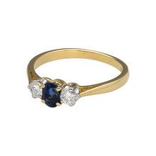 Load image into Gallery viewer, Celebrate classic beauty and symbolic style with this pre-owned 18ct yellow gold diamond and sapphire trilogy ring, featuring:

Design: A timeless trilogy setting symbolising past, present, and future—centred with a rich blue sapphire and flanked by sparkling diamonds for a perfectly balanced and elegant look.
Material: 18-carat yellow gold, offering a luxurious polished finish that enhances the depth of the sapphire and brilliance of the diamonds.

