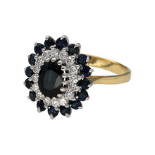Load image into Gallery viewer, Bring timeless luxury to your collection with this pre-owned 18ct yellow gold diamond and sapphire set cluster ring, featuring a striking design with rich colour and sparkling brilliance—perfect for special occasions or elegant everyday wear.

Design: At the centre of the ring sits an oval-cut sapphire measuring 8mm by 6mm, surrounded by a sparkling halo of diamonds and framed by an additional row of round sapphires, creating a layered and luxurious cluster effect.
 
