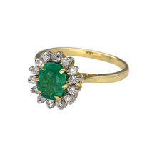 Load image into Gallery viewer, Bring rich colour and timeless elegance to your collection with this pre-owned 18ct yellow gold diamond and emerald set cluster ring, offering classic sophistication with vibrant detail—perfect for special occasions or refined everyday wear.

Design: The ring features a vivid 8mm by 6mm oval emerald at the centre, framed by a sparkling halo of diamonds in a traditional cluster setting that enhances the stone’s rich green hue.
