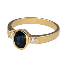 Load image into Gallery viewer, Bring classic elegance and refined sparkle to your collection with this pre-owned 18ct gold diamond and sapphire trilogy ring—a timeless design perfect for meaningful moments or everyday luxury.

Design: This elegant ring features a 7mm by 5mm oval sapphire at the centre, flanked by two round diamonds of approximately 0.06ct each, forming a balanced and sophisticated trilogy layout.

