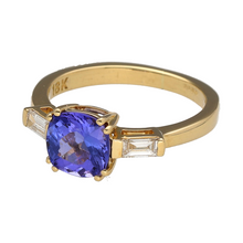 Load image into Gallery viewer, Bring vibrant colour and refined elegance to your collection with this pre-owned 18ct yellow gold diamond and tanzanite ring—a luxurious design with striking presence.

Design: The ring features a cushion-cut tanzanite measuring 7mm by 7mm, weighing approximately 1.28ct with AAA colour quality, flanked by straight baguette-cut diamonds on either side for added brilliance.

