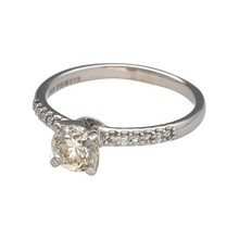 Load image into Gallery viewer, Celebrate brilliance and elegance with this pre-owned 14ct white gold diamond solitaire ring, enhanced with diamond-set shoulders for added sparkle and sophistication.

Design: The ring features a central brilliant-cut diamond of approximately 0.84ct, complemented by diamond-set shoulders that bring extra radiance to the design.
Material: Made in 14-carat white gold, the polished finish offers a bright and modern backdrop that enhances the beauty of the diamonds.
