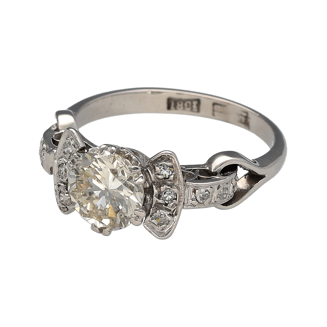 Add timeless elegance and vintage charm to your jewellery collection with this pre-owned 18ct white gold diamond vintage style solitaire ring, offering exceptional presence and classic sophistication.

Design: This ring features a striking brilliant cut centre diamond measuring approximately 1.28ct, creating a captivating focal point. Additional diamonds accent the shoulders, enhancing the overall sparkle and complementing the vintage-inspired design.