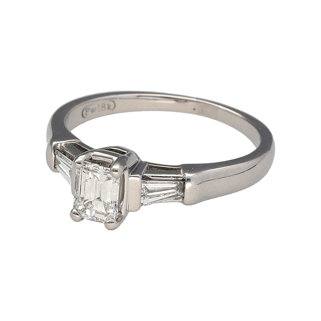 Add refined elegance and timeless sophistication to your jewellery collection with this pre-owned 18ct white gold diamond solitaire ring, offering striking structure and classic appeal.

Design: This ring features an emerald cut diamond at the centre measuring approximately 0.50ct, creating a sleek and elegant focal point. It is flanked by two tapered baguette cut diamonds, one on each side, each measuring approximately 0.10ct, adding balance and architectural detail to the design.
