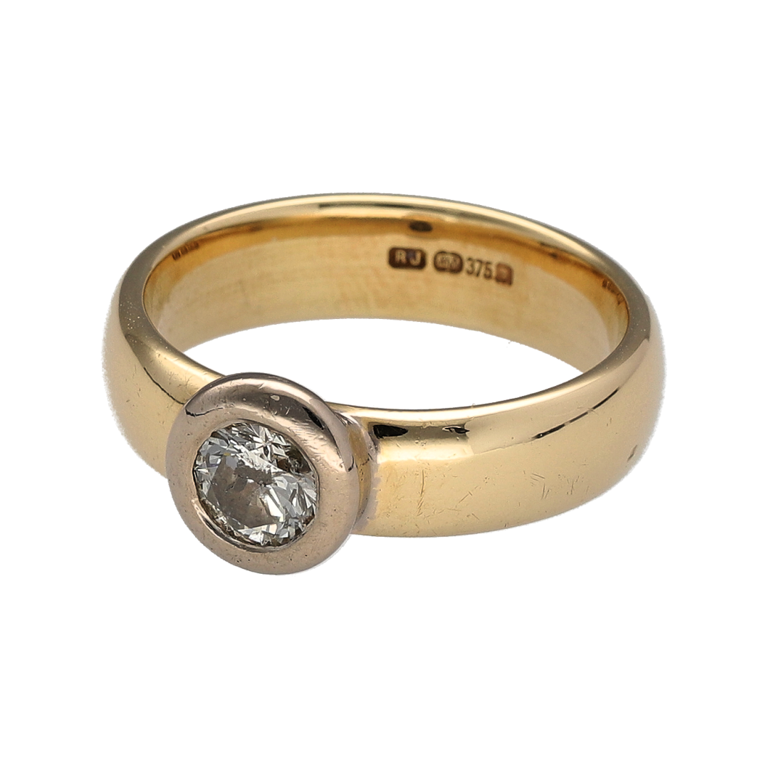 Make a confident and contemporary statement with this pre-owned 9ct yellow and white gold diamond rubover set solitaire wide band ring—an elegant design combining clean lines with impressive sparkle.

Design: The ring features a brilliant cut diamond weighing approximately 0.46ct, securely rubover set to create a smooth and modern finish. The 5mm wide band offers a bold, structured profile, giving the solitaire design a strong and distinctive presence on the hand.