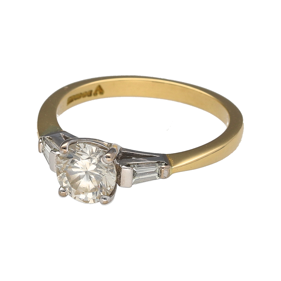 Make a breathtaking statement with this pre-owned 18ct yellow gold diamond set solitaire ring—an exceptional design combining classic brilliance with elegant side detail.

Design: The ring features a stunning brilliant cut centre diamond weighing approximately 0.93ct, beautifully complemented by a baguette cut diamond on either side, each approximately 0.09ct. The three-stone arrangement creates a refined and balanced silhouette, blending timeless solitaire style with Art Deco-inspired accents.