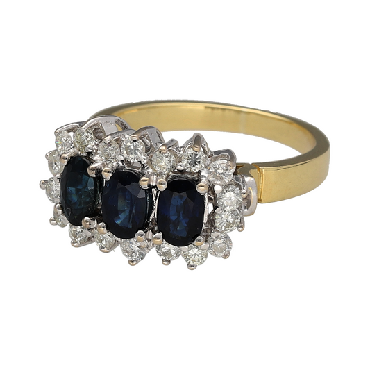 Add luxurious colour and exceptional sparkle to your jewellery collection with this pre-owned 18ct yellow gold diamond and sapphire set trilogy cluster ring—an eye-catching and elegant piece perfect for special occasions.

Design: This ring features three oval sapphire gemstones, each measuring approximately 6mm by 4mm, arranged in a classic trilogy formation. Each sapphire is surrounded by brilliant-cut diamonds, creating three radiant cluster settings across the finger.