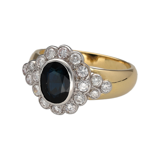 Add timeless elegance and striking colour to your jewellery collection with this pre-owned 18ct yellow gold diamond and sapphire set cluster ring—an exquisite piece perfect for special occasions or everyday luxury.

Design: This ring features a captivating oval sapphire at the centre, measuring approximately 8mm by 6mm, surrounded by brilliant-cut diamonds that extend onto the shoulders for a beautifully balanced and radiant look.