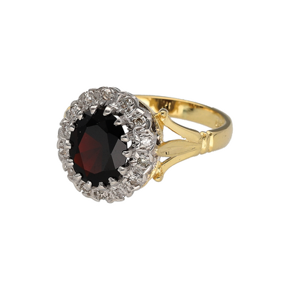 Add vintage-inspired elegance and rich colour to your collection with this pre-owned 18ct yellow and white gold diamond and garnet cluster ring, offering timeless beauty and luxurious detail—perfect for special occasions or refined everyday wear.

Design: The ring features a striking 9mm by 7mm oval-cut garnet at the centre, surrounded by a halo of sparkling diamonds that enhance the deep red tones of the gemstone.