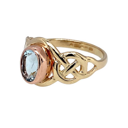 Preowned 9ct Yellow & Rose Gold & Blue Topaz Set Clogau Ring with Celtic style shoulders. The ring is in size J to K with the weight 2.50 grams. The topaz stone is 7mm by 5mm